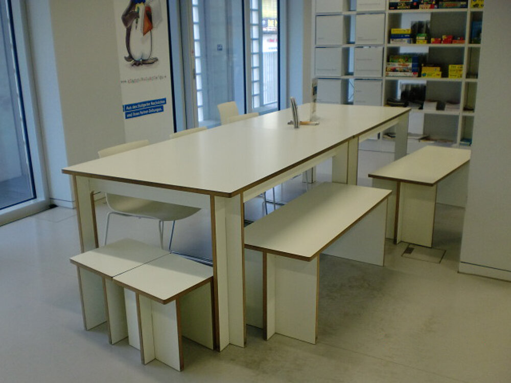 Ein modernes Büro mit einem Tojo Tisch und passenden Bänken, die klar und funktional gestaltet sind, perfekt für einen offenen Arbeitsbereich.