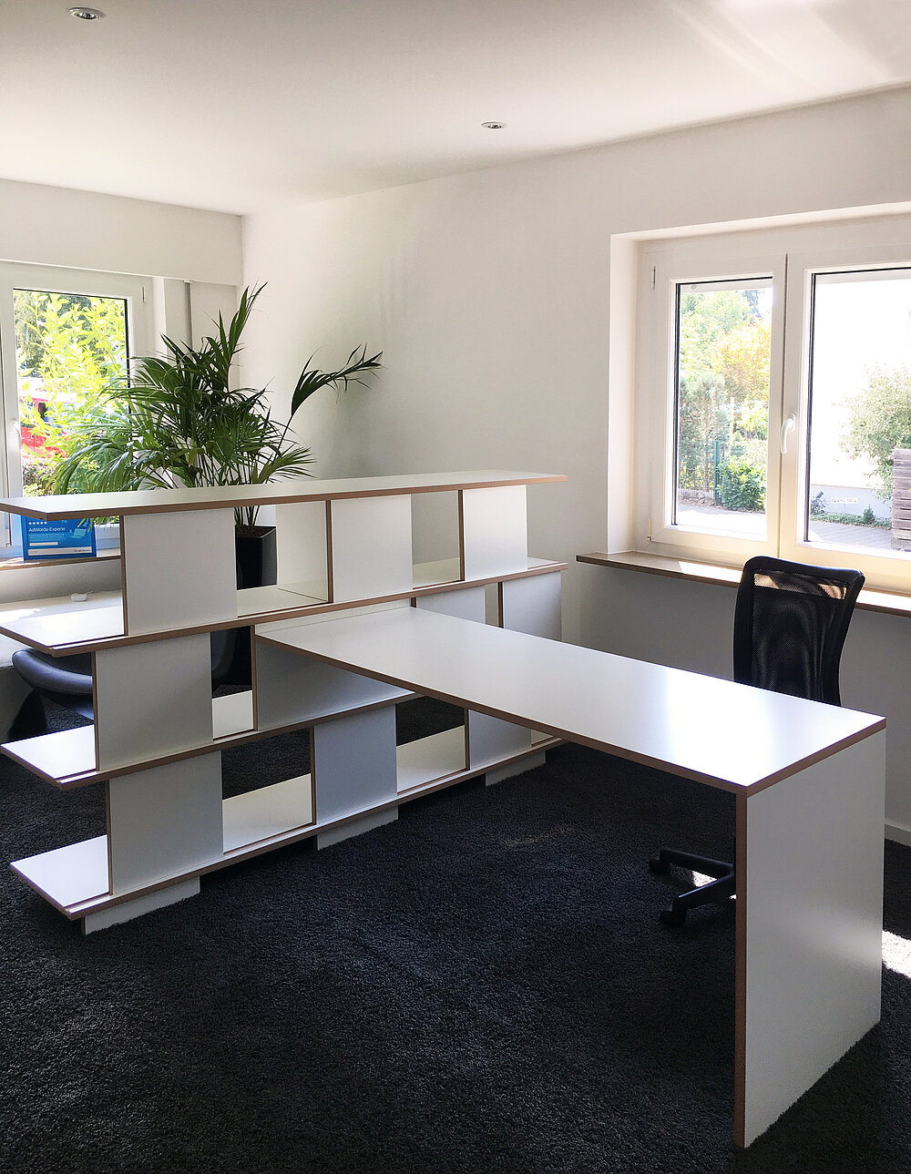 Moderne Büroeinrichtung mit einem kreativen Regal- und Tischsystem von Tojo, das eine funktionale und ästhetische Raumaufteilung ermöglicht.