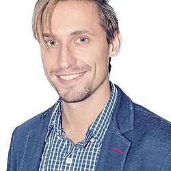 Porträt von Designer Prieler in kariertem Hemd und Sakko, vor hellem Hintergrund