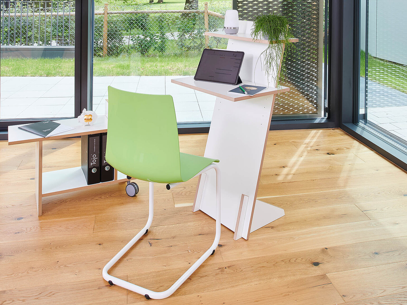 Tojo Pult, als funktionale Arbeitsstation mit einem Laptop, einem Regal und einem modernen Stuhl. Ideal für kreative Arbeitsumgebungen.
