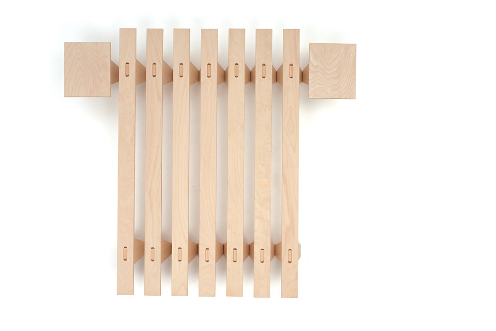 Zusammengeklapptes Tojo lieg Bettgestell von oben fotografiert, aus naturbelassenem Holz mit klaren Linien – kompaktes, stapelbares Design