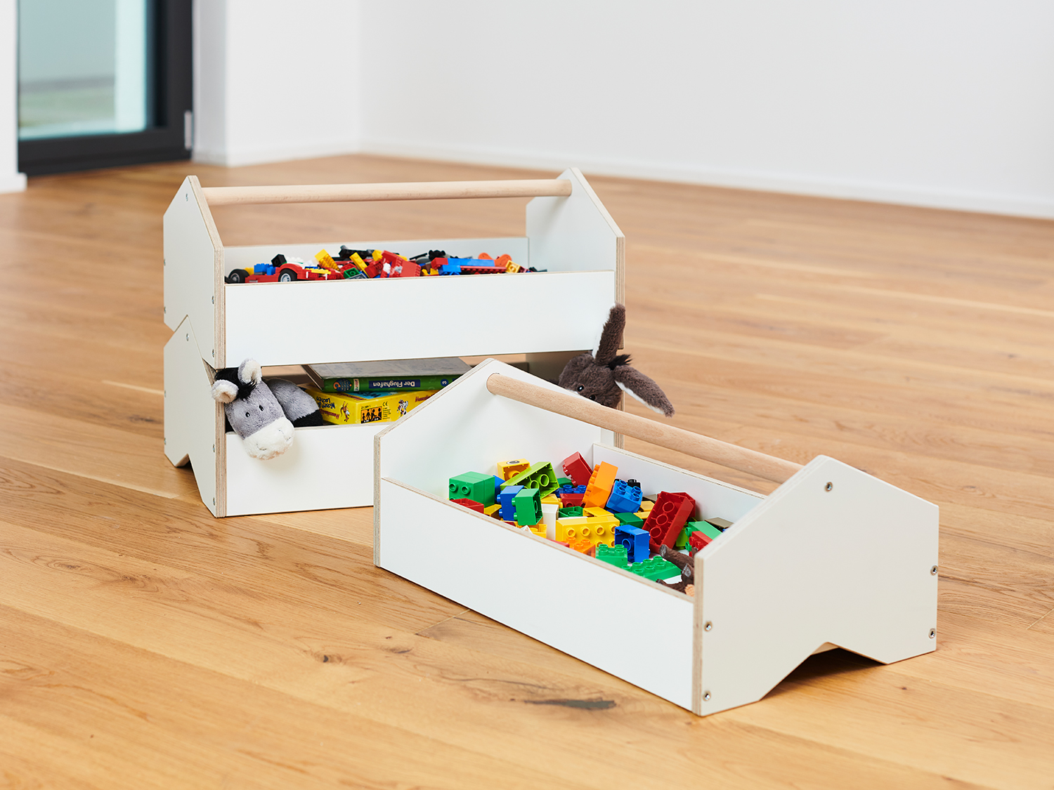 Set von zwei Tojo Kindermöbel "Kisten" aus weißem Holz, gefüllt mit bunten Spielzeugbausteinen, ideal für die Aufbewahrung im Kinderzimmer
