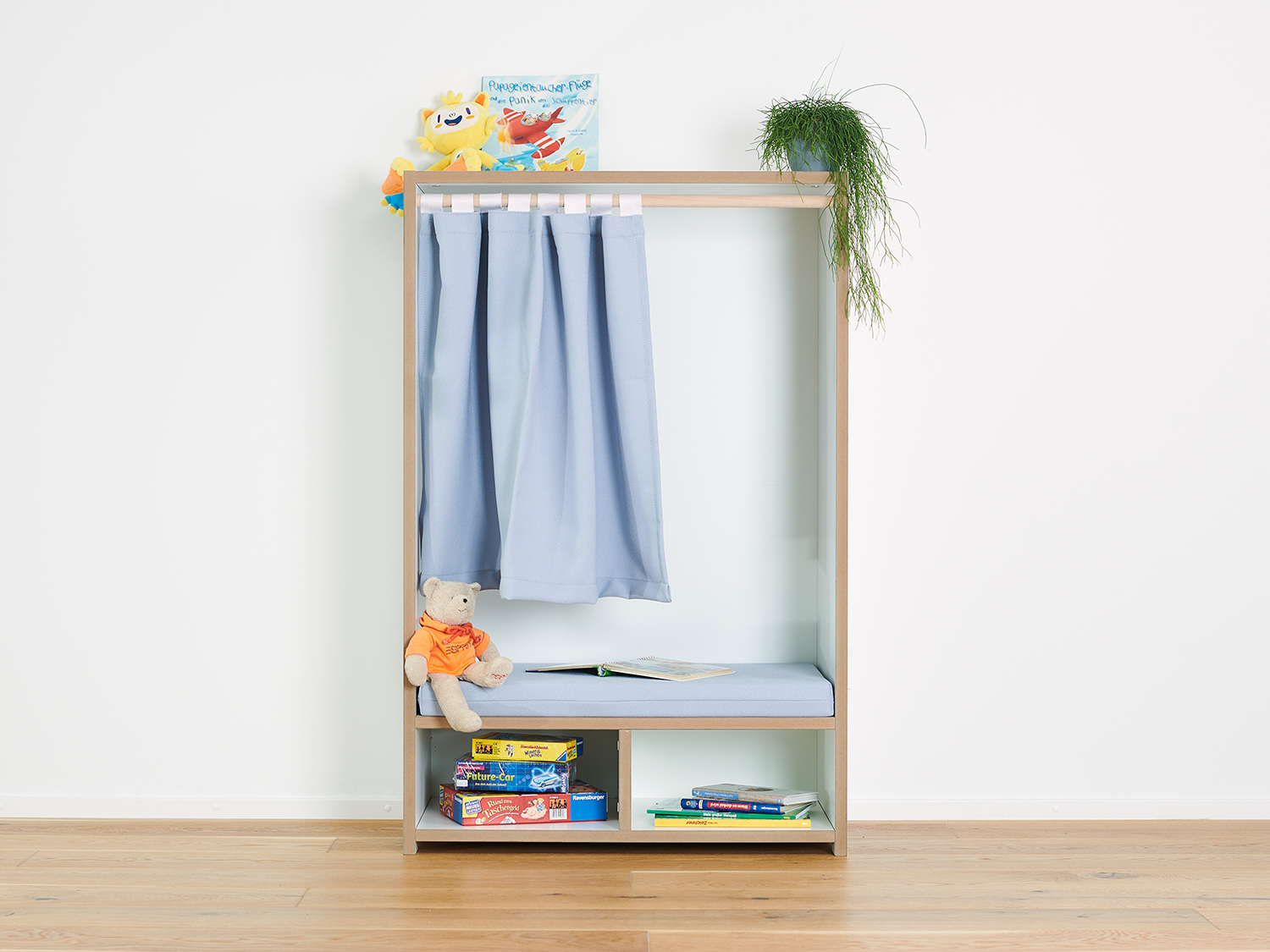 Tojo Nische Aufbewahrungseinheit für das Kinderzimmer mit Vorhängen, die den Stauraum für Spielzeug und Kleidung verbergen, sowie offenen Regalen und Fächern zur praktischen Aufbewahrung von Kinderutensilien.