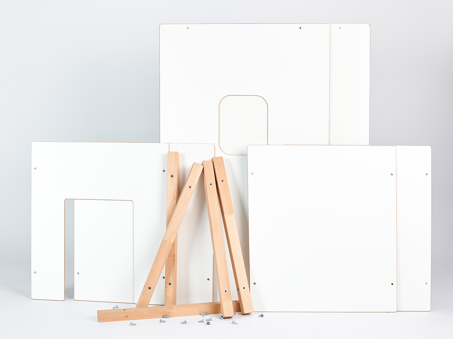 Einzelteile der Tojo Wand für das Kinderzimmer, bestehend aus weißen Trennwänden und Holzstangen für die Montage, die eine flexible Raumaufteilung ermöglichen.