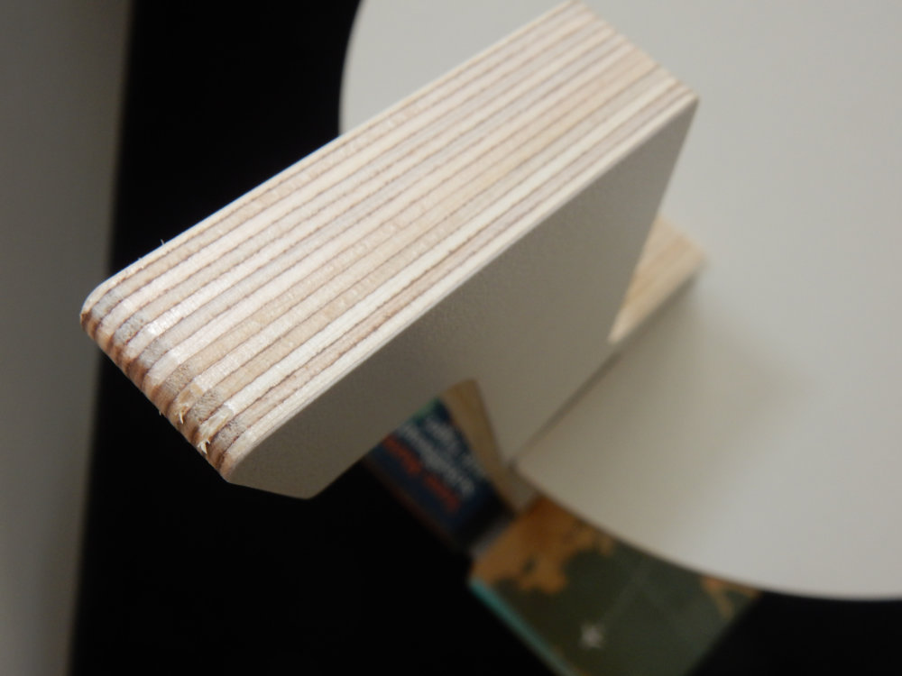 Detailansicht der Tojo Lesestelle, die den stabilen Holzstapel und die elegante Tischkante zeigt, ideal für das Aufbewahren von Büchern und Accessoires.