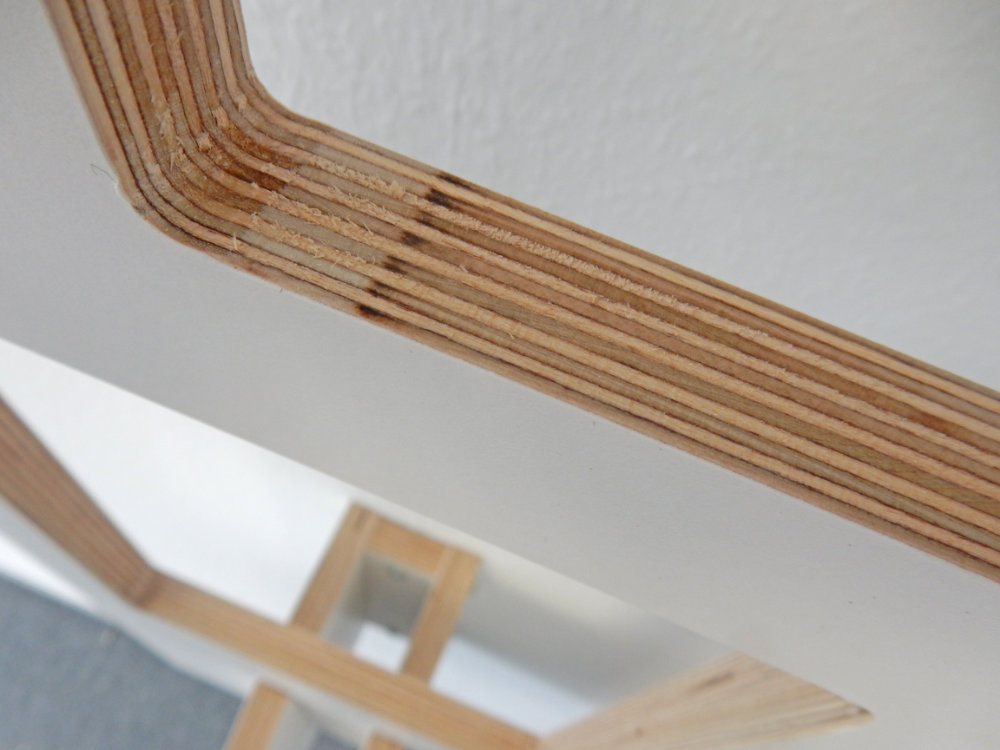 Nahaufnahme der präzisen Verarbeitung der Kante des Tojo Lesestoff Wandregals, das mit sichtbaren Schichten aus hochwertigem Holz gefertigt ist.