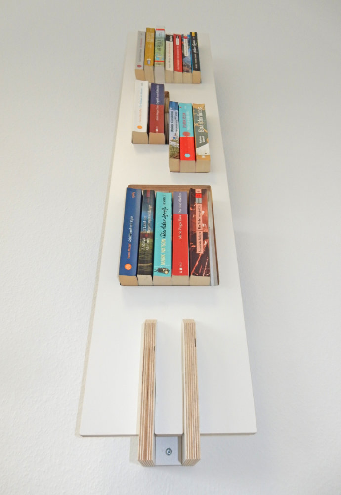 Tojo Lesestoff Wandregal, das eine Sammlung von Büchern in verschiedenen Farben und Größen zeigt