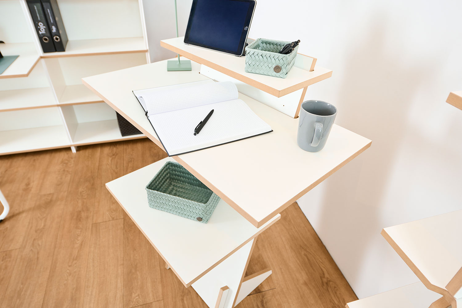 Nahaufnahme des Tojo Pults, auf dem ein Laptop, Notizbuch, Stifte und Tassen abgestellt sind.