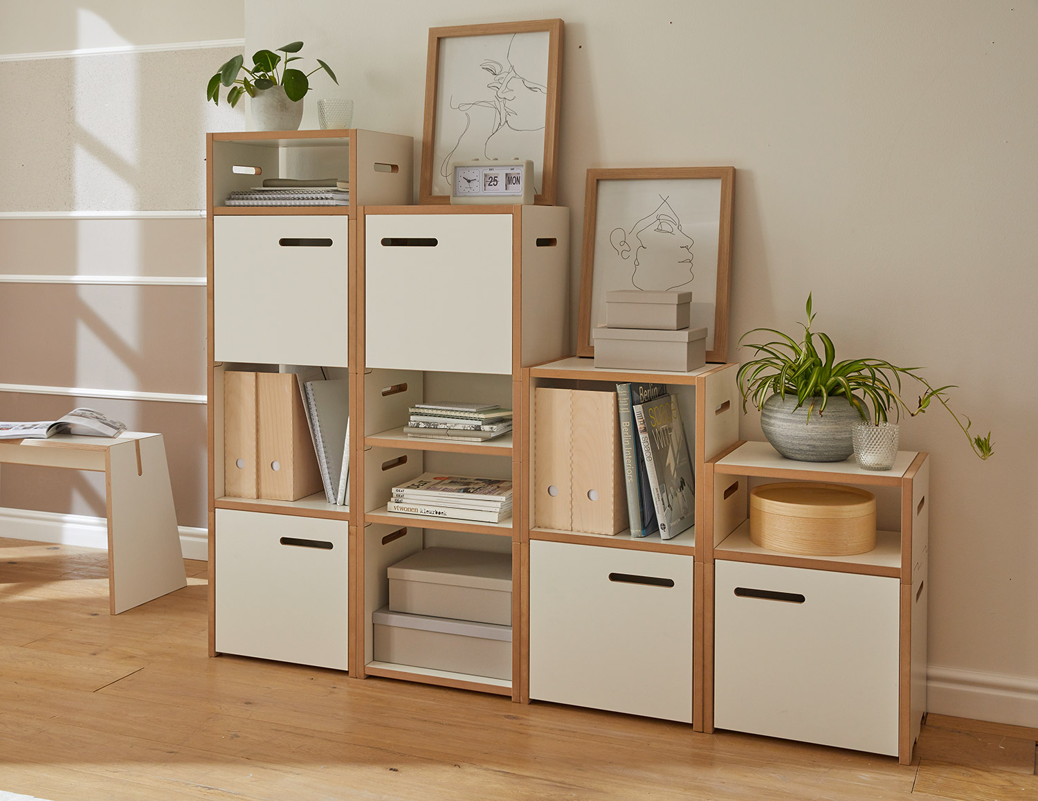 Modulares Regalsystem „halbstark“ von Tojo in wohnlicher Umgebung – weiße Elemente mit Holzrahmen, kombiniert aus offenen und geschlossenen Fächern