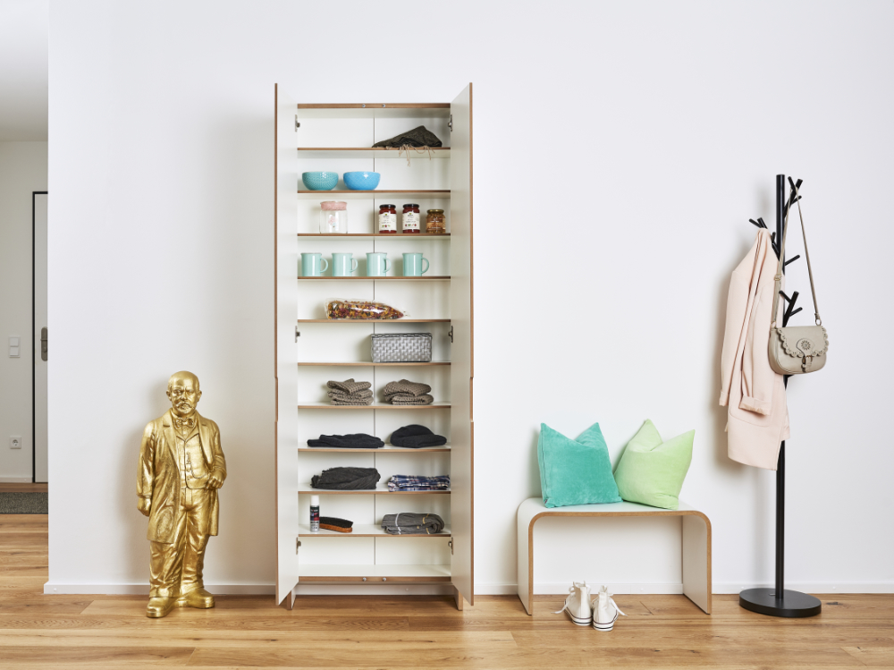 Tojo Schrank „flachmann“ offen genutzt als Schuhregal mit Accessoires, in modernem Wohnraum mit goldener Figur und Garderobe